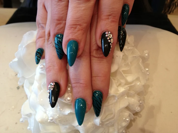 thin and long, pointy and sharp nails, decorated with iridescent rhinestone stickers, and black hand-drawn zebra pattern