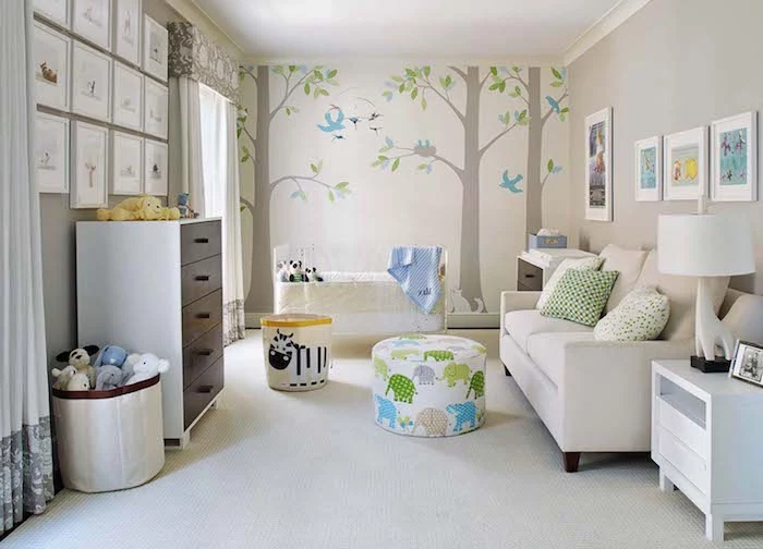 woodland wall decal, with threes and birds, in large baby nursery, with white crib and sofa, lots of framed drawings, chest of drawers and cupboard