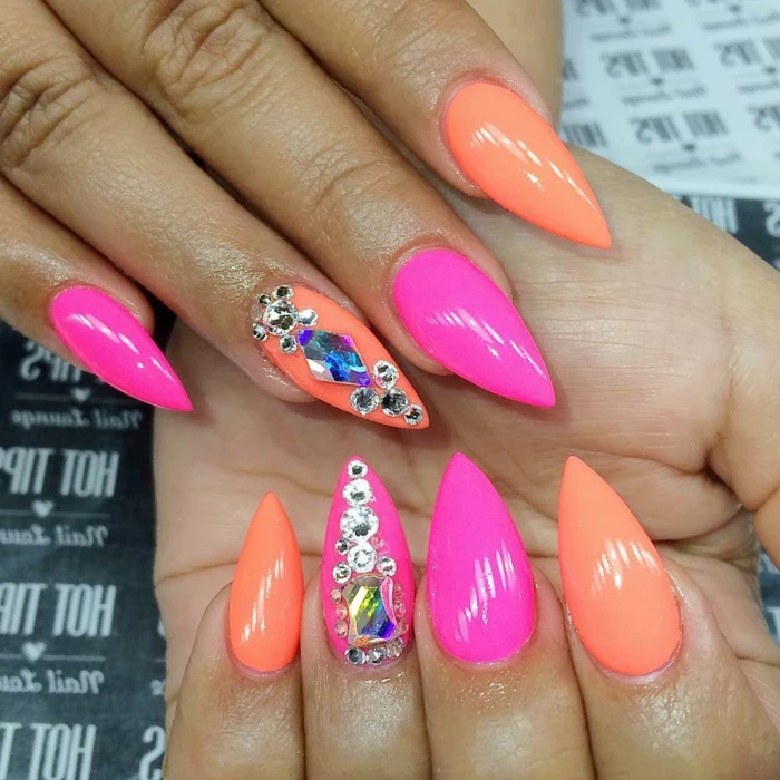neon orange and pink nail polish, stilleto nail designs, decorated with silver and blue rhinestone stickers
