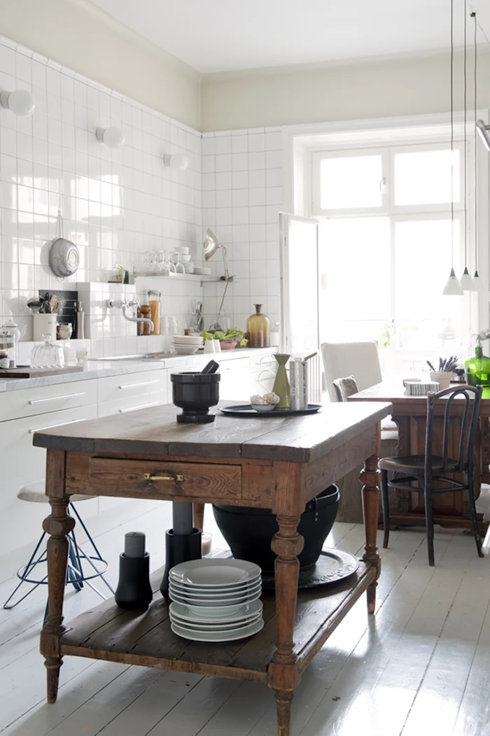 vintage wooden kitchen island, inside bright room, with white tiles on the walls, white cupboards and sink
