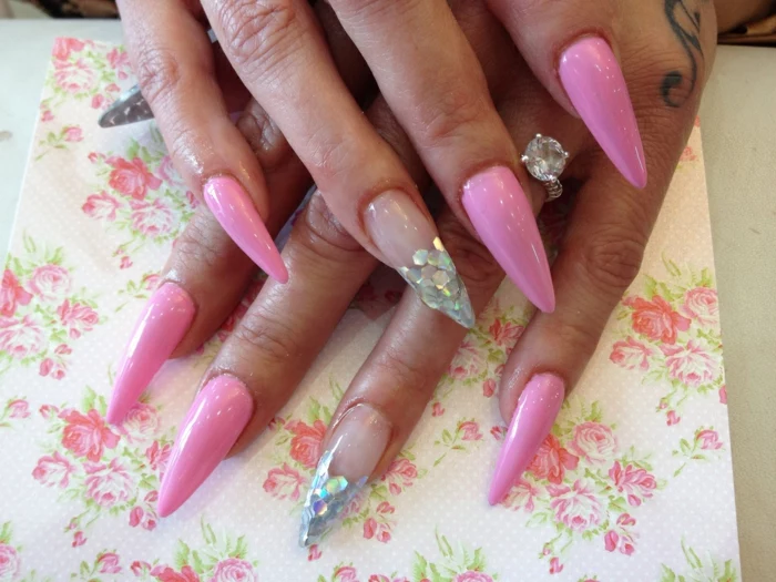 barbie pink manicure, decorated with silver, fish scale-like glitter, and clear nail polish, on long claw nails 