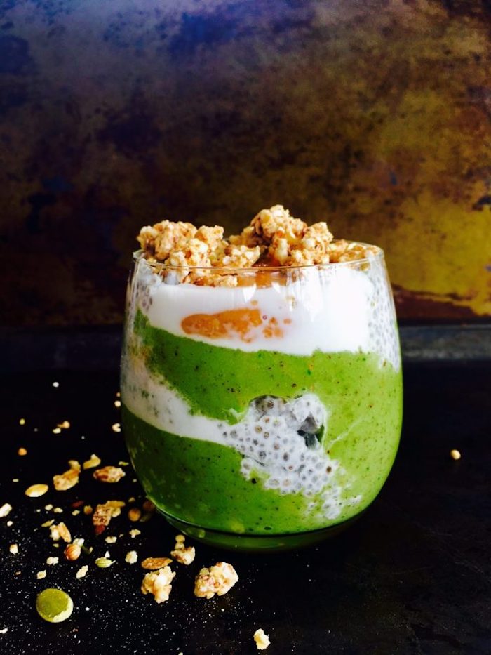 chia and yoghurt, mixed with a green smoothie, made from kiwi, and topped with beige crunchy nuts