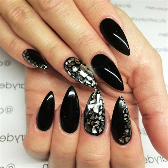 stylish smooth and shiny, black stiletto nails, some decorated with tiny, silver metallic shards