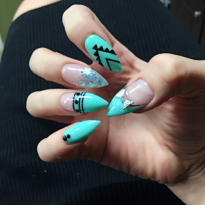 stilleto nail designs, summery manicure with turquoise, and clear nail polish, decorated with black, hand-painted figures, silver glitter and diamante bow ornament