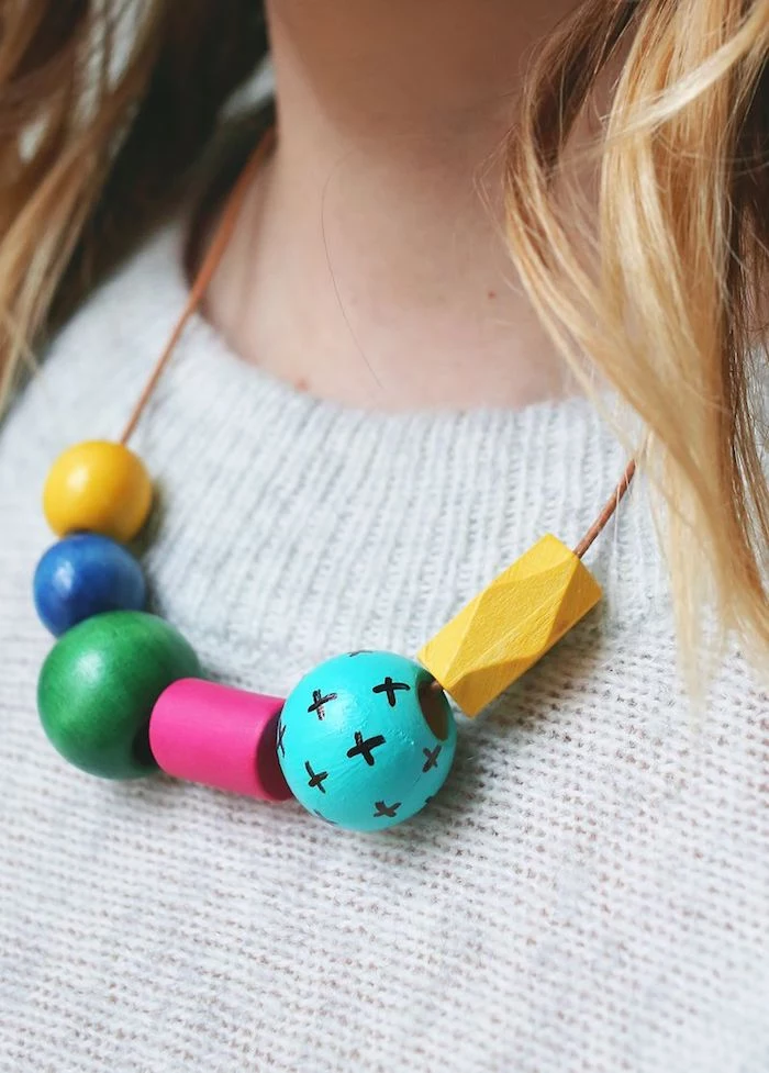 handmade necklace with wooden beads, in different shapes and colors, some decorated with hand-drawn patterns, mothers day gifts, on blonde woman's neck