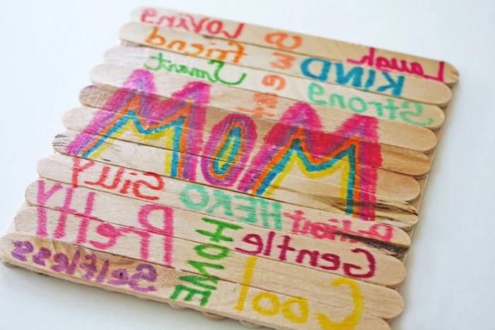 wooden ice-cream sticks, stuck together to form a coaster, decorated with greetings for mom, written with markers in different colors