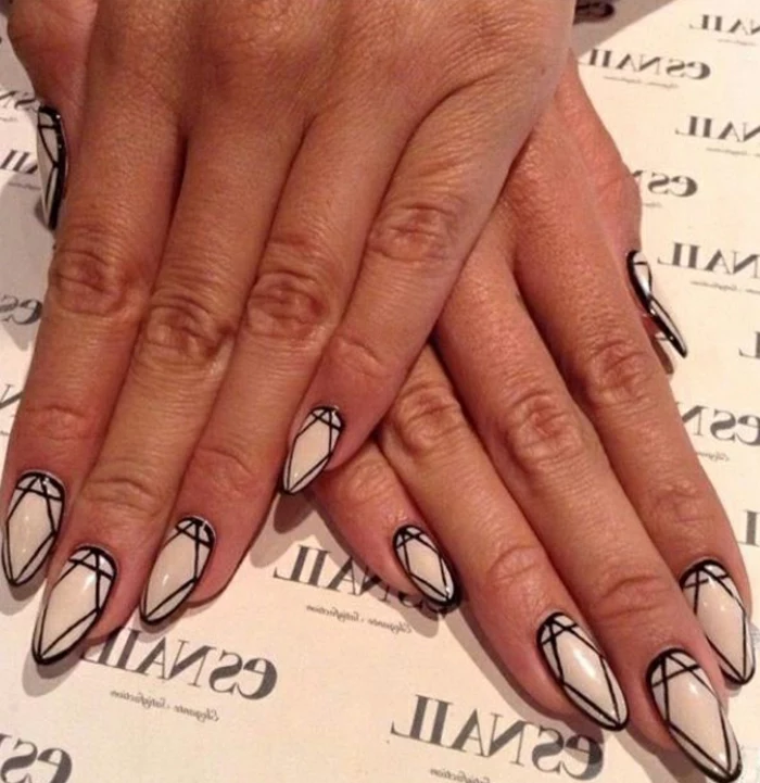 pale cream nail polish, on short stiletto nails, decorated with diamond shapes, outlined in black