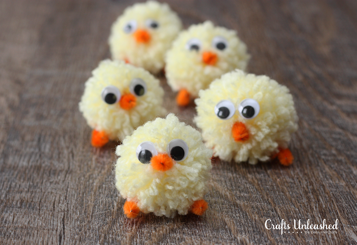 five chick decorations, easter crafts for kids, made from pale yellow pom poms, with tiny legs and beaks, made from orange fuzzy wire, and eye stickers