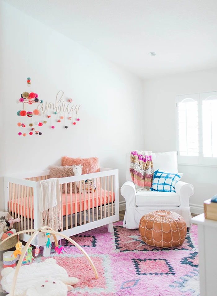 coral pink and beige bedding, and two matching fluffy cushions, in white crib, on pink carpet, with black and orange motifs, baby girl themes, peruvian aesthetic 