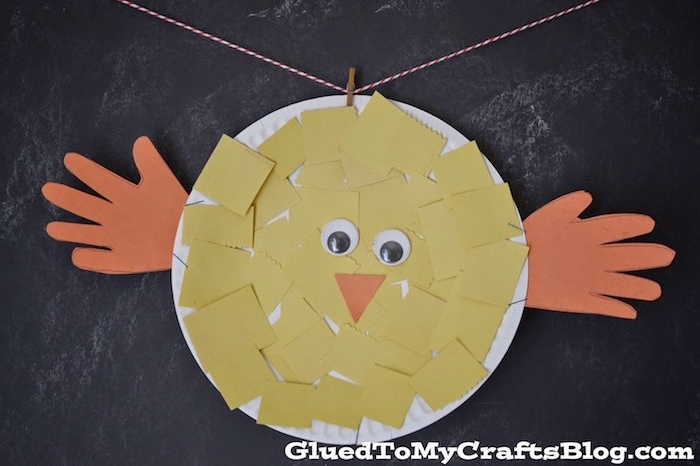 easter crafts for preschoolers, chick ornament made from round, white paper plate, covered in yellow pieces of paper, with orange hand-shaped cutouts for wings