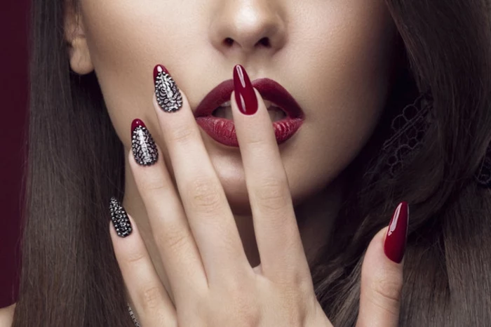 classic deep red nail polish, on long stiletto nails, decorated with silver glitter, worn by brunette woman, with matching re lipstick
