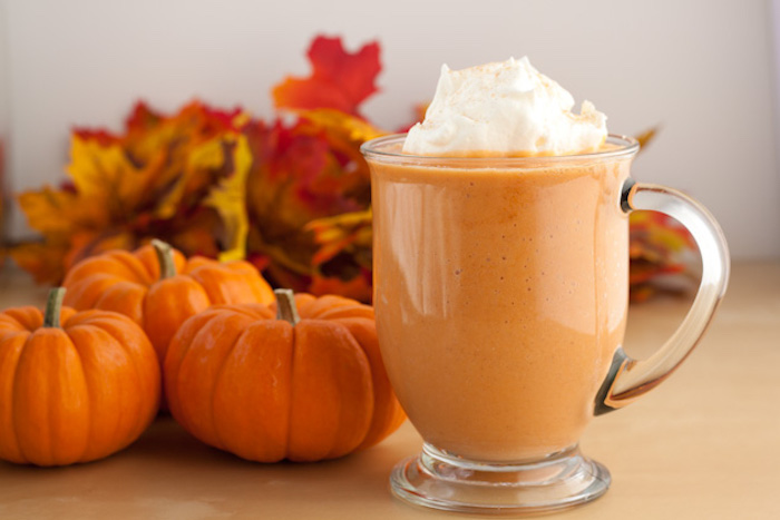 mini pumpkins and dried autumn leaves, near a clear glass with handle, filled with pale orange drink, topped with whipped cream, easy smoothie recipes 