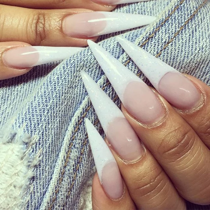 very long and sharp, french manicure-style claw nails, with extremely long white tips, covered with pale glitter