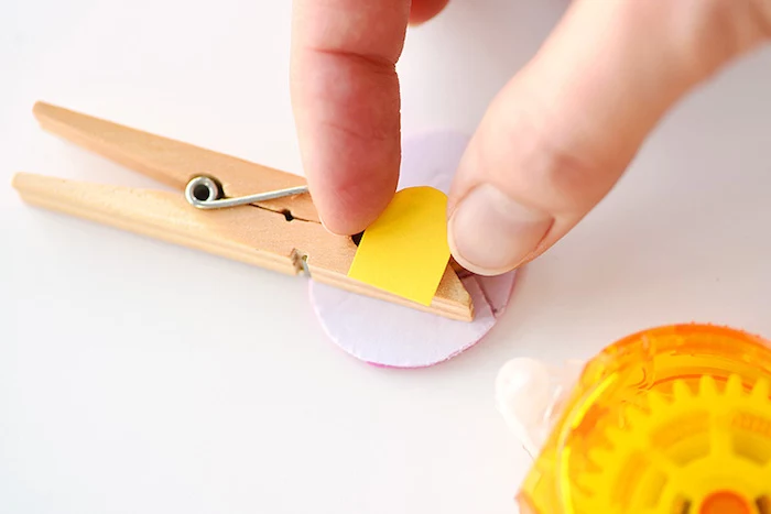 putting yellow cutout, on top of two-sided sticky-tape, stuck to a clothespin, and eggs-shaped card cutout, easter projects, fun and easy