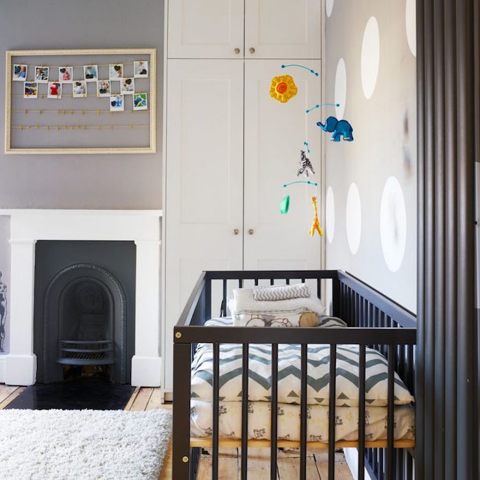 minimalist boys room ideas, gray and white walls, black and white fireplace, black wooden crib, mobile with animals