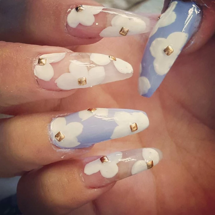 sheer pale pink, and light pastel blue nail polish, with white hand-drawn flowers, and tiny golden stickers, on long claw nails