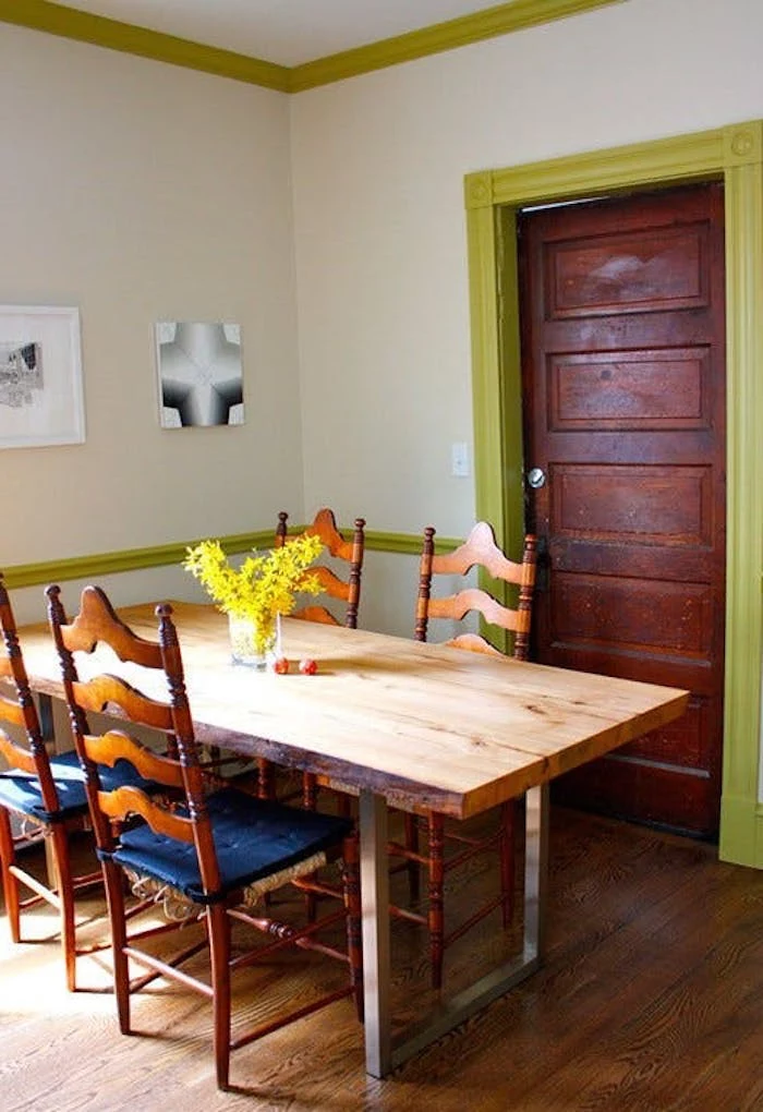 table made from natural wood and metal, with an industrial twist, and four retro chairs, in dining room with white walls, and pale green plaster details