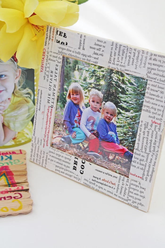 newspaper clippings collage, covering photo frame, containing image of three little children, mother's day gifts for grandma, yellow flower and more photos nearby