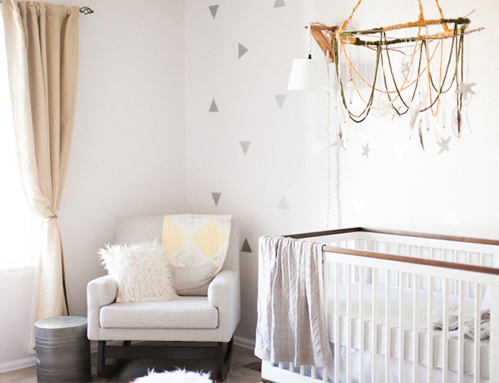 rocking armchair in white, near wooden crib in white and brown, in bright nursery, decorated with light neutral colors