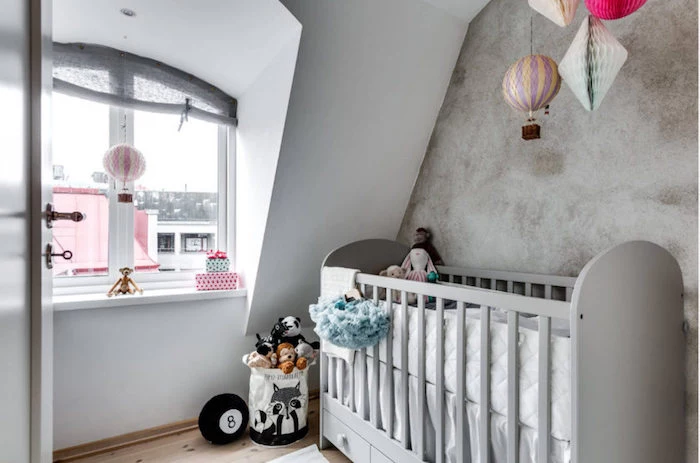modern girl nursery themes, pale gray baby crib, in room with white and gray wash walls, lots of toys in pastel colors