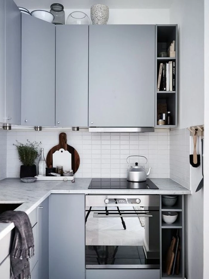 cabinets in duck's egg blue, inside small blue gray kitchen, with kettle and several vases, modern and functional