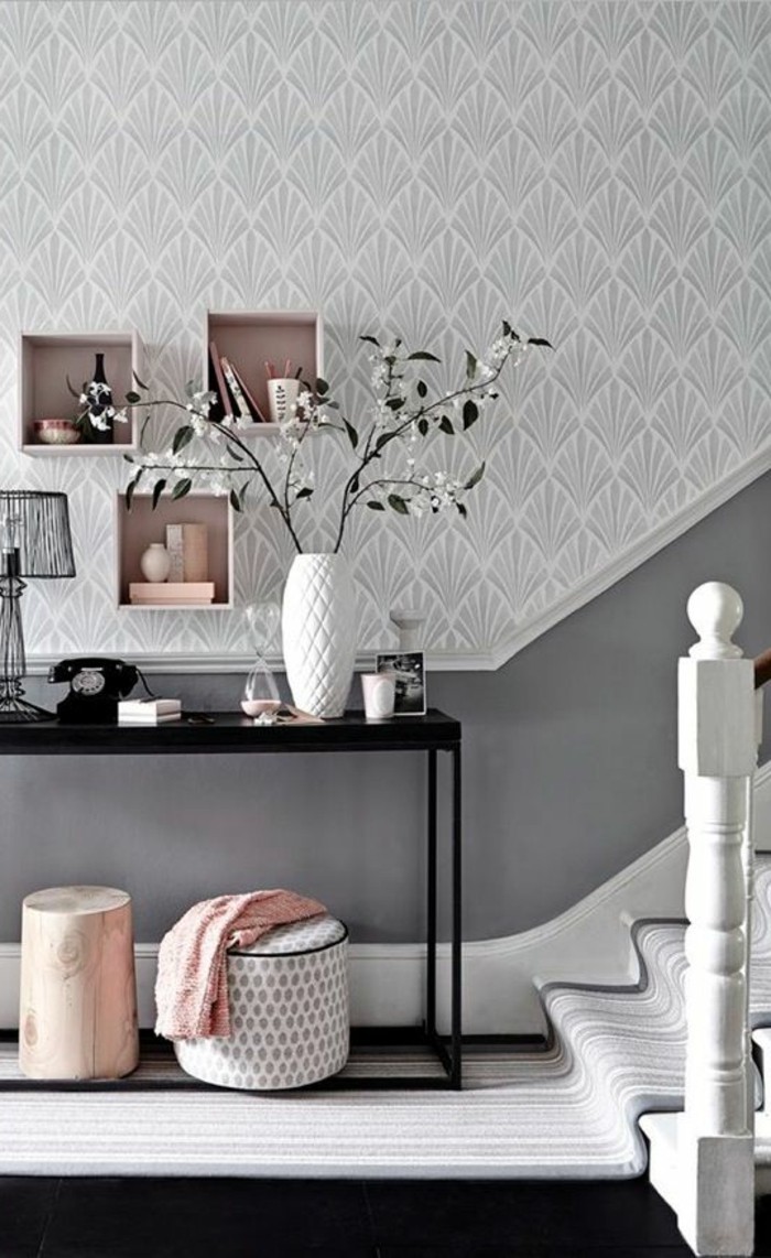 landing or hallway, with pale gray ornate wallpaper, and dark gray paneling, near stairway with light striped rug, pale pink and white decorations