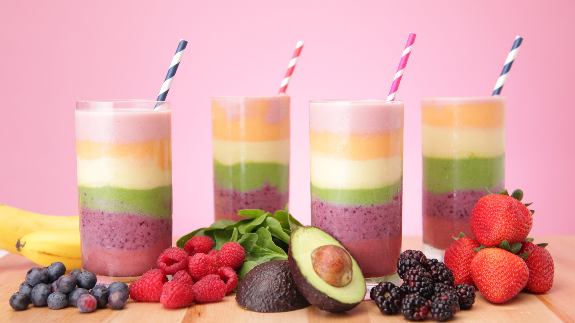 avocado and grape, blackberry and raspberry, banana and spinach smoothie, layered fruit and spinach smoothie, in four glasses with straws