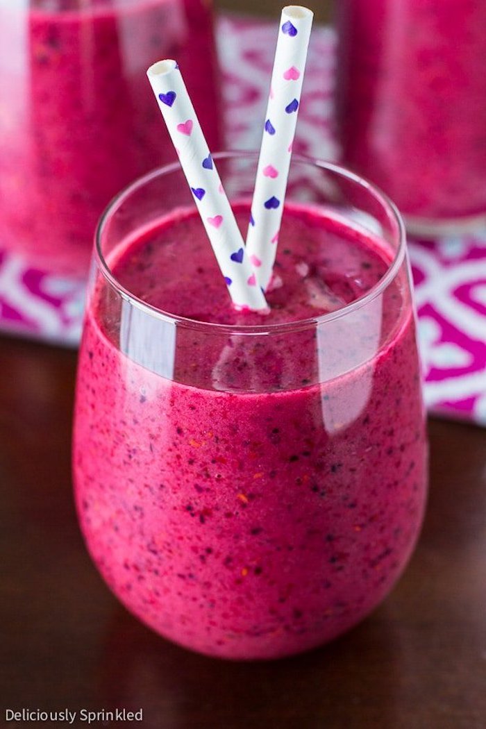 white straws with pink and purple heart print, inside a tumbler glass, filled with hot pink, blended berry juice, smoothie recipes, healthy ideas