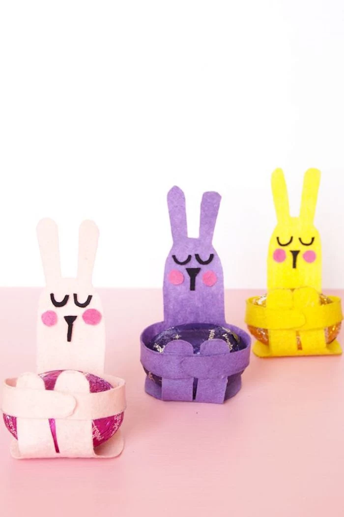 egg holders shaped like rabbits, made from pale pink, purple and yellow felt, with collaged faces, containing eggs in matching colors