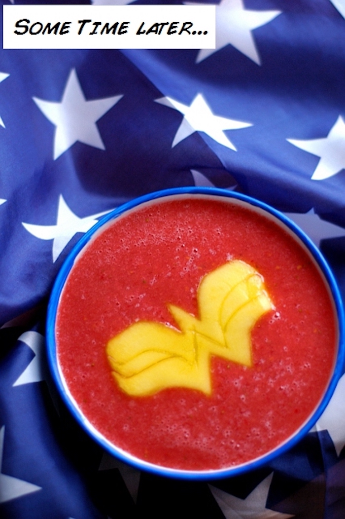 wonder woman-inspired fruit drink, how to make a fruit smoothie, blended berries topped with a w-shaped mango slice, blue cloth with white stars in background