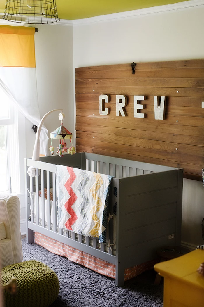 colorful mobile over gray wooden crib, boys room ideas, near white wall, with wooden board, decorated with pale gray letters, spelling the word crew