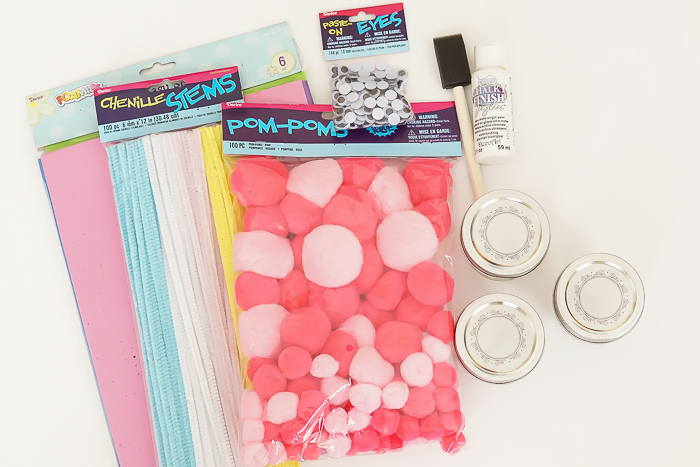 three small mason jars with lids, pack of pink pom poms, fuzzy wire in different colors, glue and brush, and colored paper