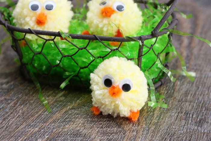 green easter grass, inside a rough metal basket, with two chick ornaments, made from pale yellow pom poms, easter crafts for kids, another chick next to the basket