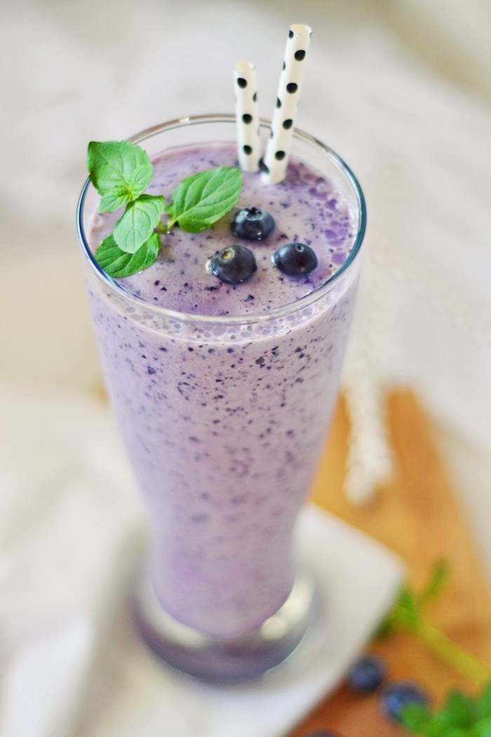 tall clear glass, filled with creamy pale purple mixture, smoothie recipes, topped with blueberries, and fresh mint leaves