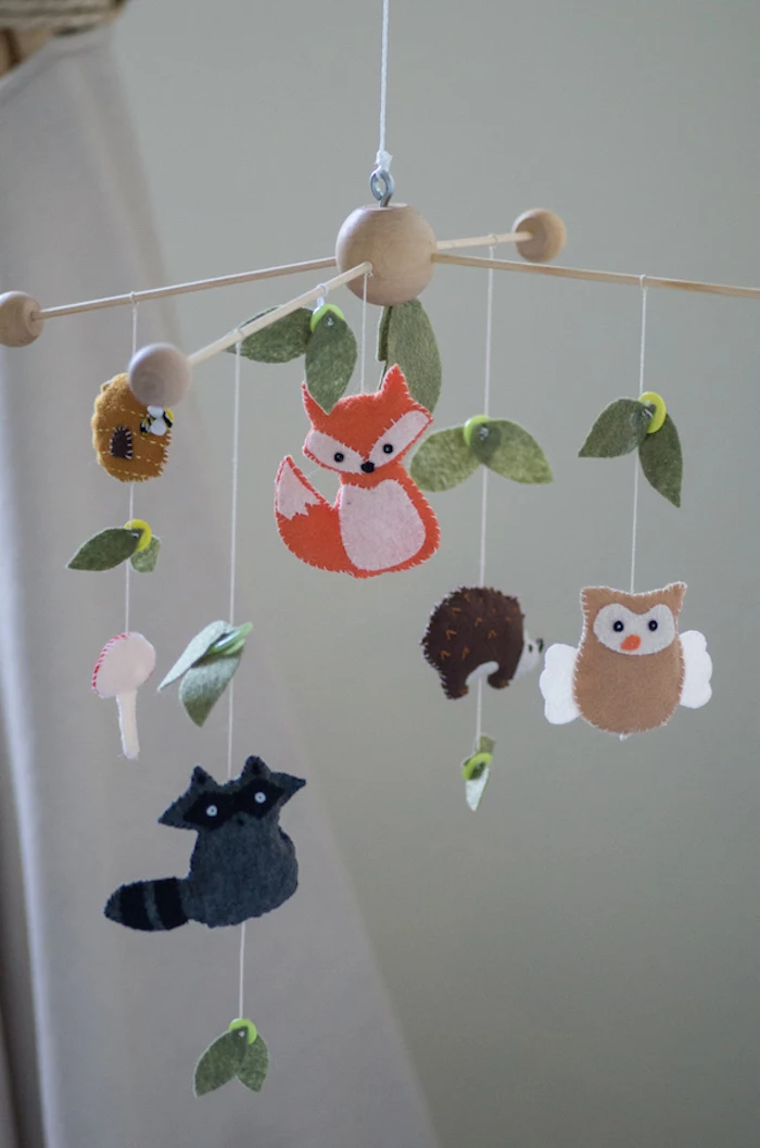 baby nursery ideas, mobile made from light wood, and decorated with leaves, animals and mushrooms, made from felt