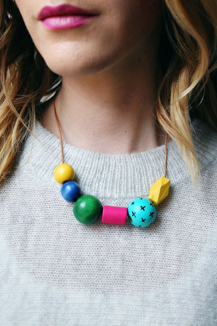 necklace made of wooden beads, in different colors and shapes, hanging around a blonde woman's neck, mother's day gift ideas, cyclamen pink lipstick