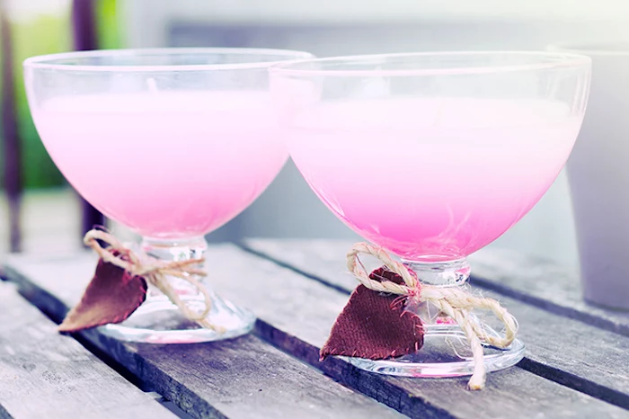 mothers day presents, two clear cocktail glasses, containing pale pink candles, decorated with dark red fabric hearts