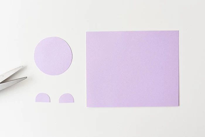large piece of light purple paper, near three cutouts, one round and two half-circles, craft ideas for kids, near metal scissor blades