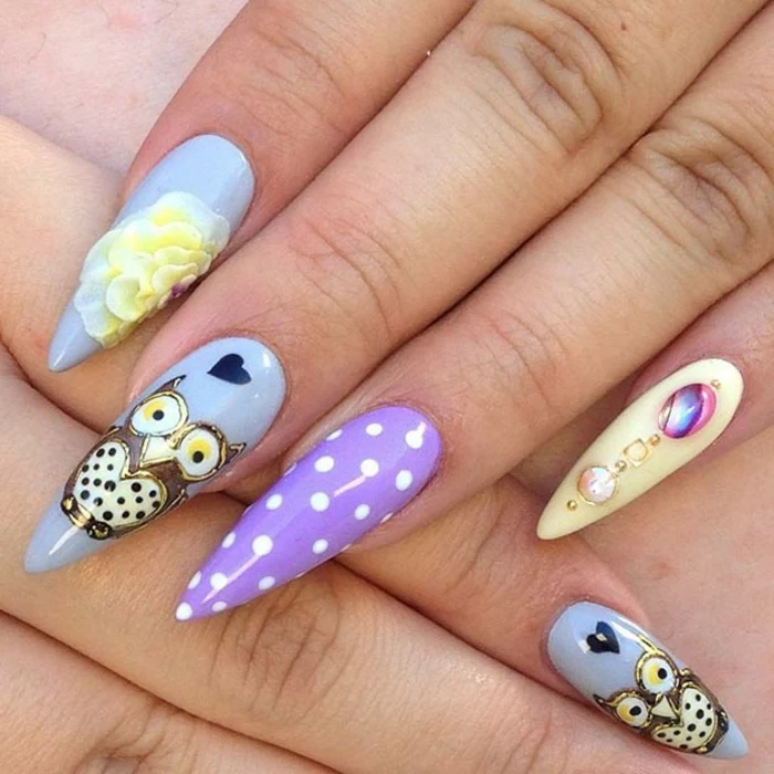 polka dots and iridescent stickers, yellow acrylic 3D flower, and little owl drawing, on stiletto acrylic nails, painted in pale blue, violet and light yellow nail polish