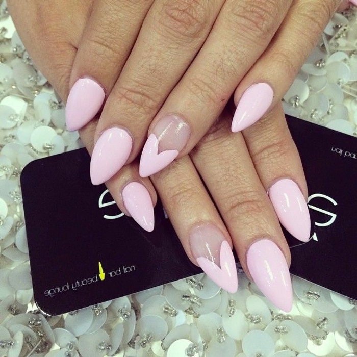 short stiletto nails, sharp and painted in pale, pastel pink nail polish, with heart details