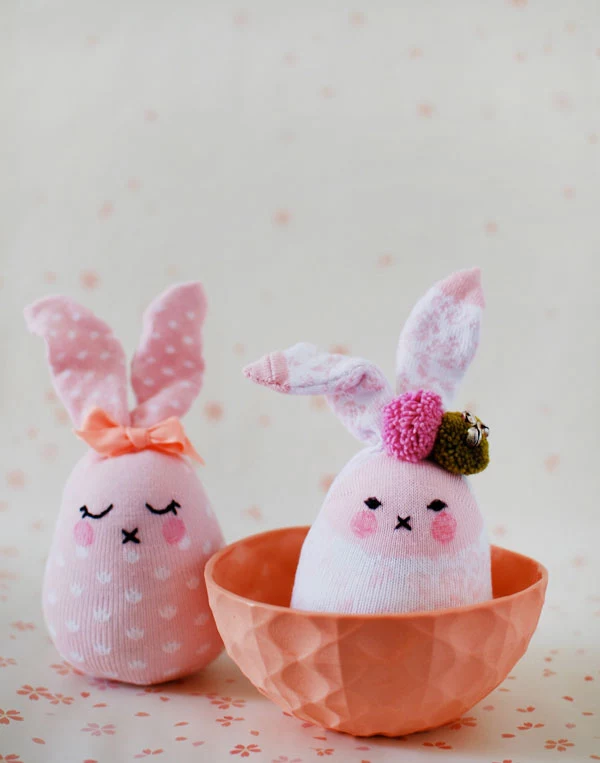 stuffed bunny dolls, made from two pink socks, with white pattern, black embroidered faces, easter crafts for kids, decorated with bow and pom poms
