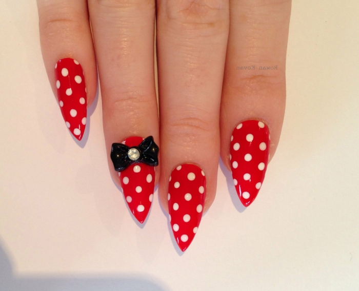 minnie mouse style nails, bright red with white polka dots, decorated with black, plastic bow-shaped sticker, long pointy manicure
