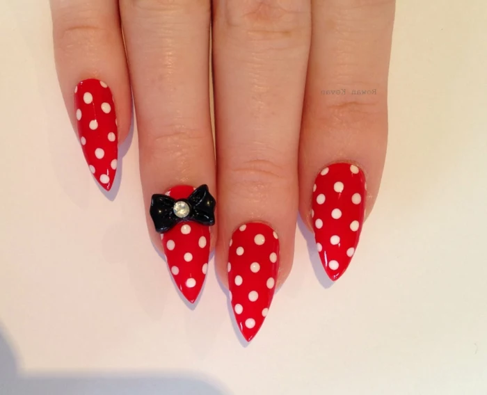 minnie mouse style nails, bright red with white polka dots, decorated with black, plastic bow-shaped sticker, long pointy manicure