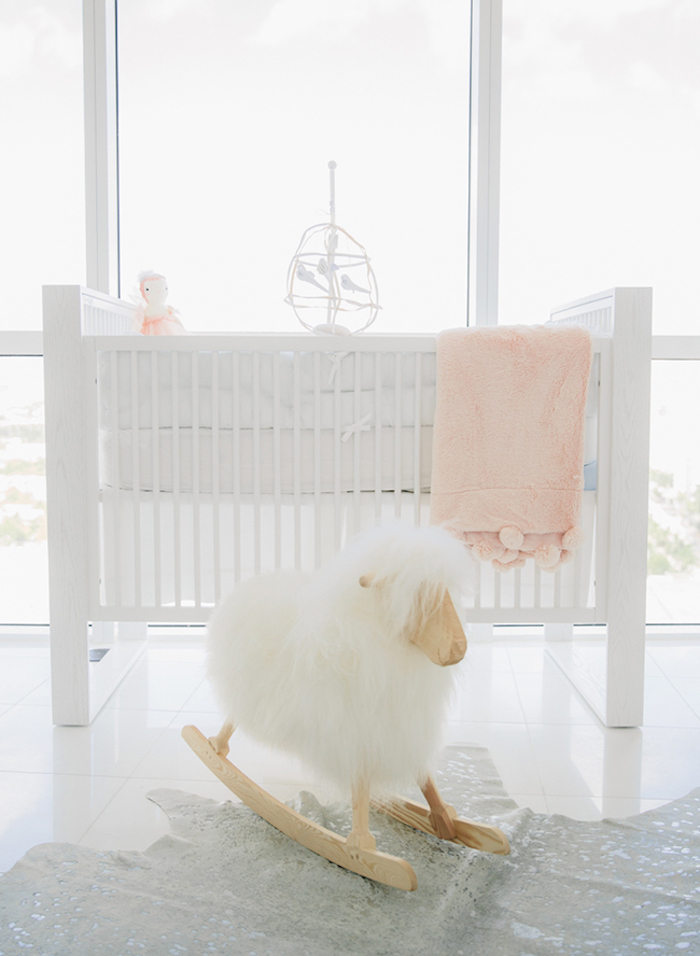 baby girl nursery ideas, fluffy rocking sheep toy, near pure white crib, with pale pink doll and blanket, light gray shiny tiled floor