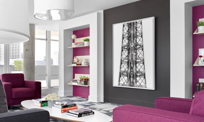 purple and dark gray details on white walls, in a large living room, with two purple armchairs, colors that go with gray walls, white oval coffee table, with several books and flowers