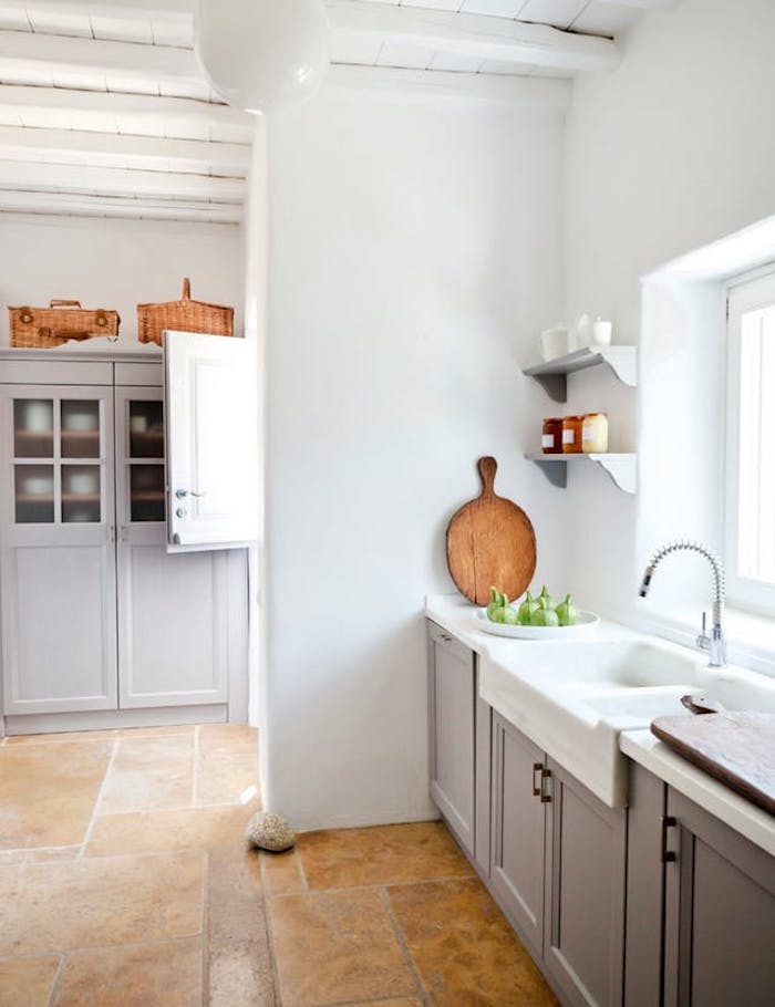 mink-colored cabinets, white sink with modern metal tap, inside bright kitchen, with white wall and ceiling, and beige stone floor, country kitchen decorating ideas