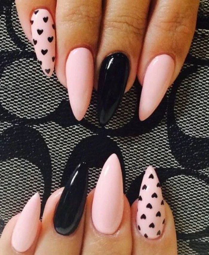 pale pink and black stiletto nails, some decorated with small, hand-drawn hearts print, others left plain