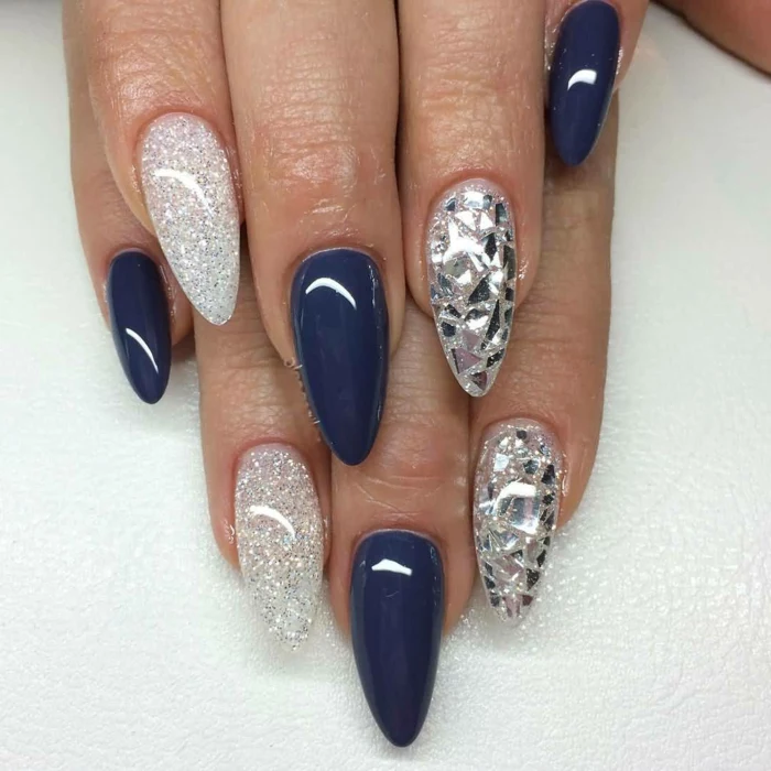 silver glitter and metallic shards, decorating stiletto acrylic nails, covered in dark blue, smooth and shiny nail polish