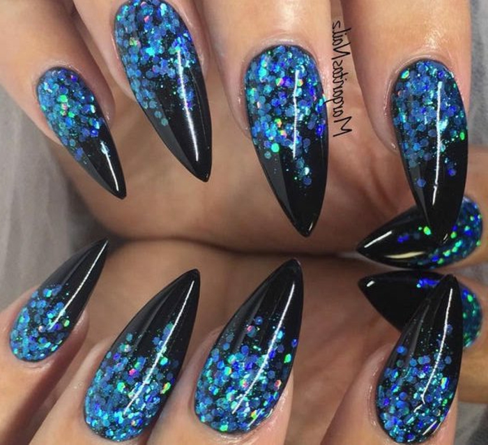 blue glitter in different shades, on black stiletto nails, sharp and long, with a shiny and smooth finish