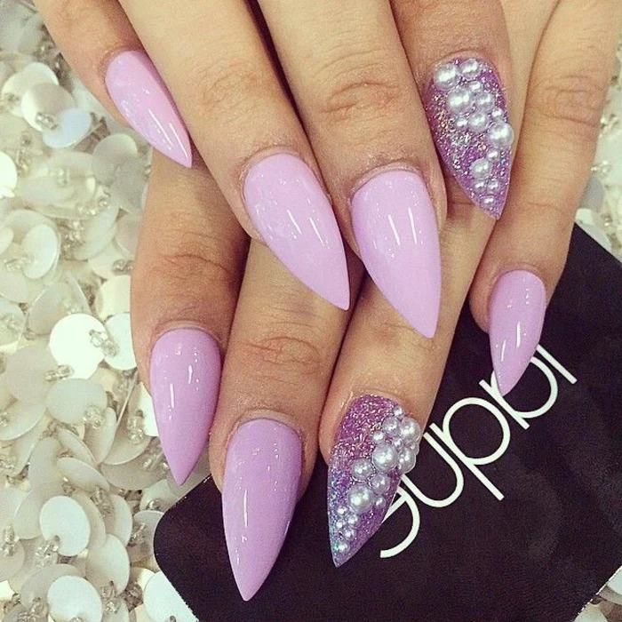 light pastel violet nail polish, smooth and shiny, with silver pearl-stickers, and violet glitter, on stiletto acrylic nails